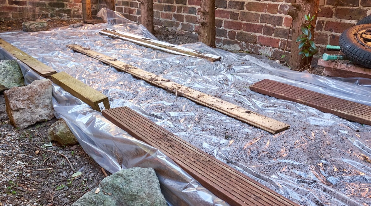 The soil is covered with a translucent sheet of plastic to warm the soil. Sheets of plastic are pressed down with wooden blocks.