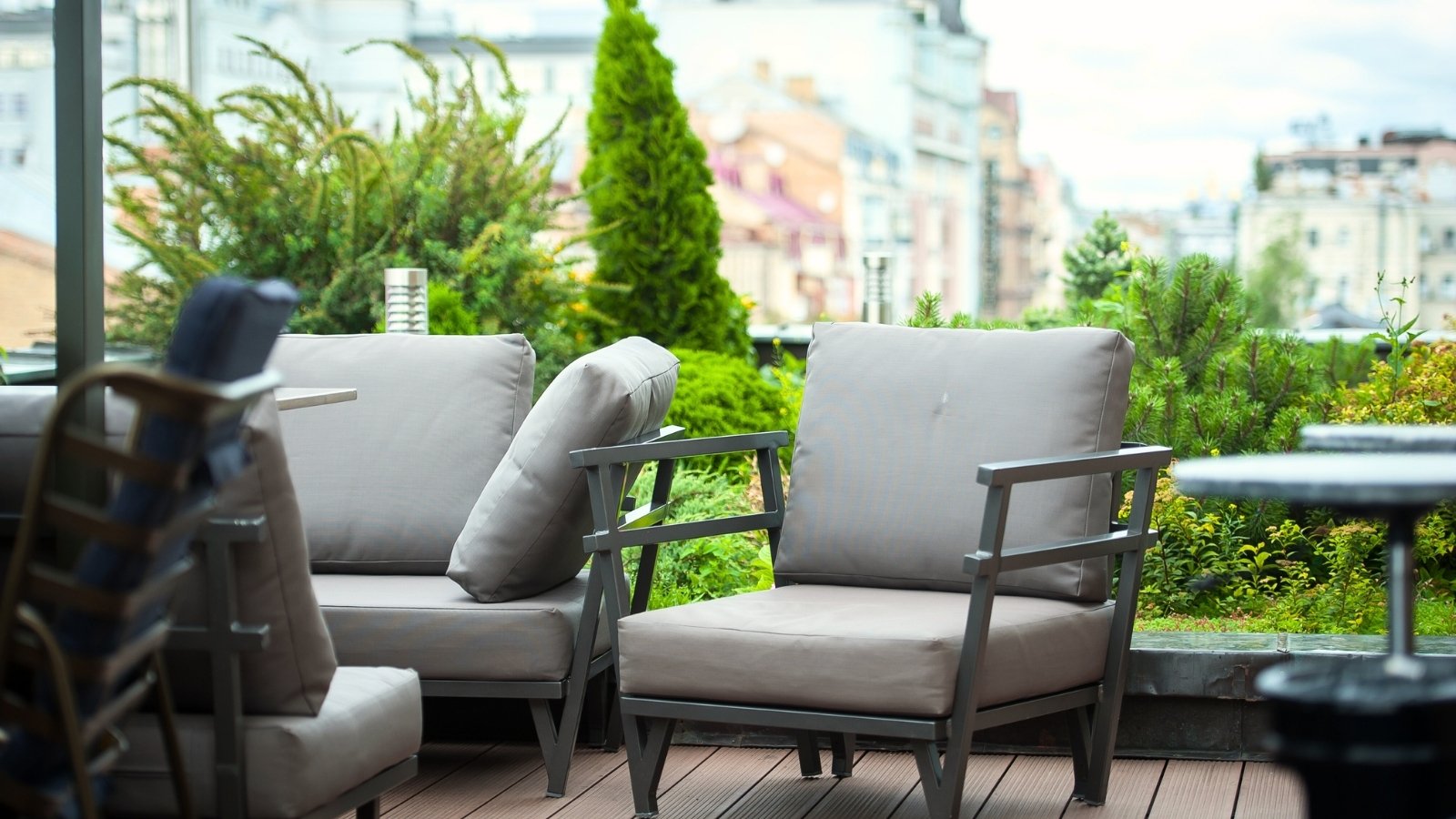 Close-up of a roof terrace with a green garden and garden furniture, including armchairs, a sofa, and tables for relaxation.