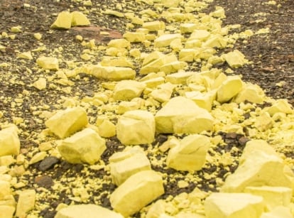 Close-up of yellow colored stones with a powdery texture scattered on top of soil.