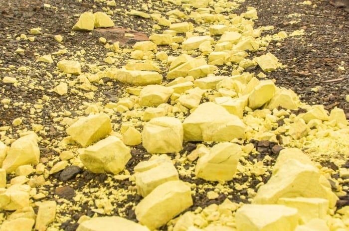Close-up of yellow colored stones with a powdery texture scattered on top of soil.