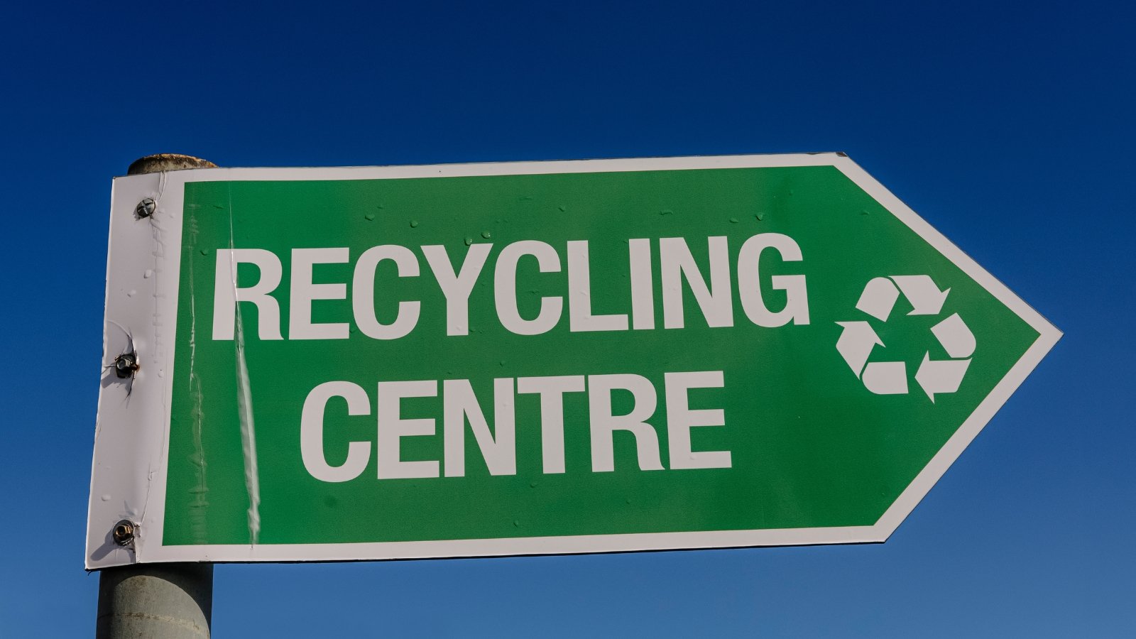 A street sign pointing in the direction of the recycling center