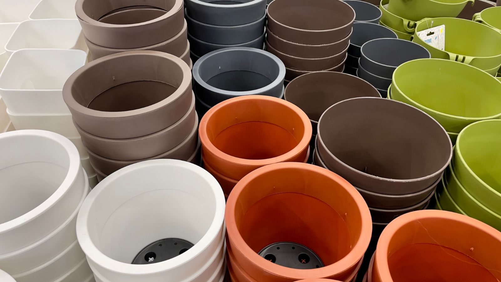A shot of multiple empty pots for plants with different sizes, shapes, colors and materials, all placed on top of each other in aa well lit area