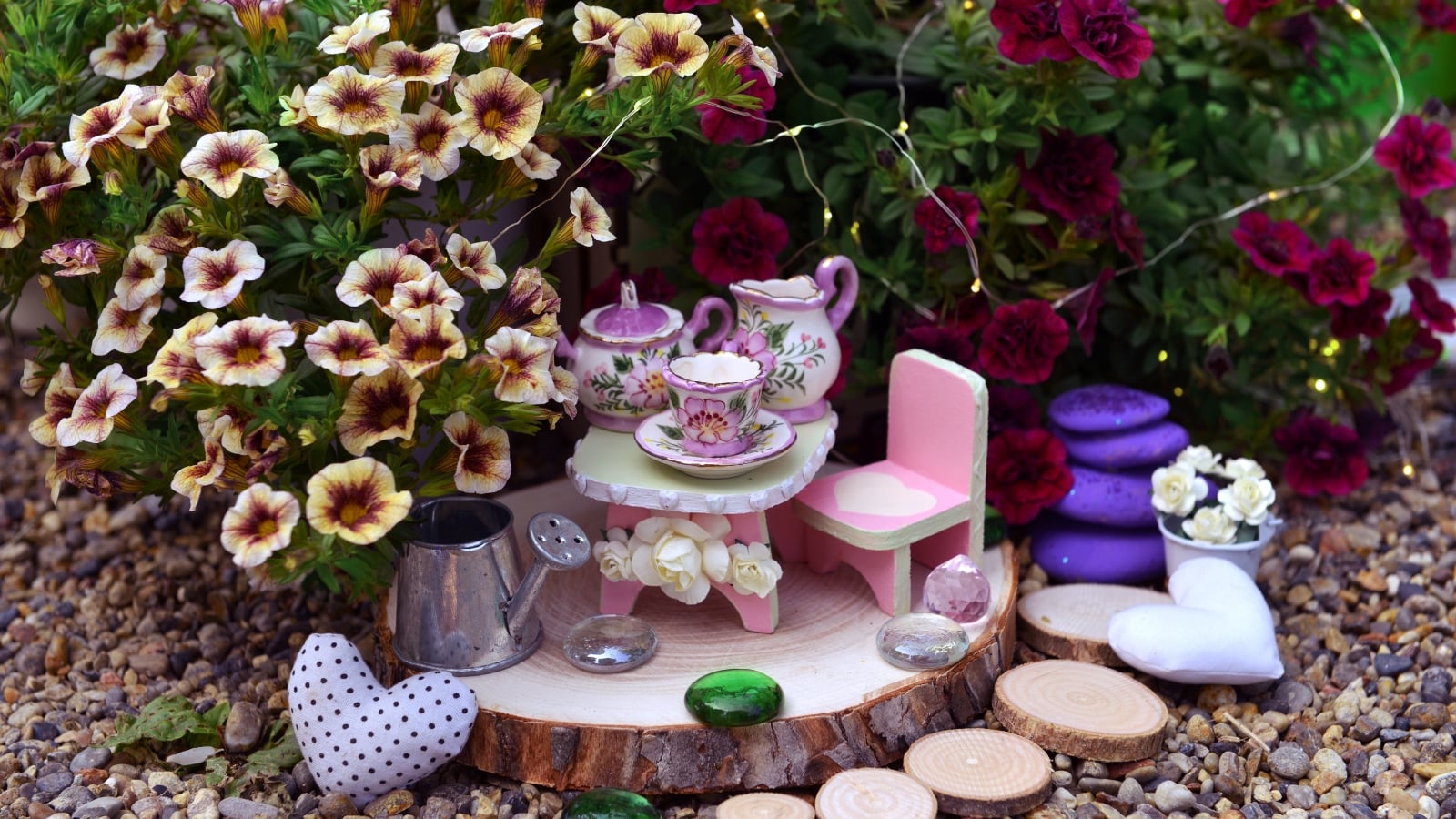 Calibrachoa 'INCALIBLANC' with small white flowers and green leaves, set beside a decorative dining setup with teacups and chairs.