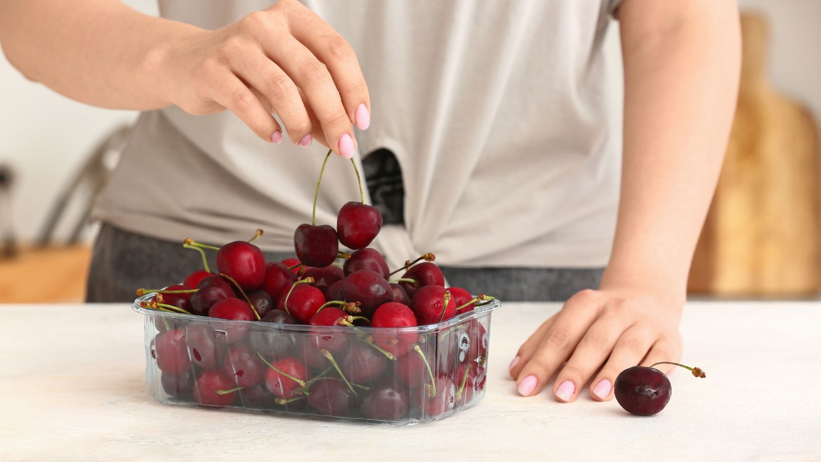 A close-up shot of a person inspecting freshly harvested round fruits, placed on top of a table indoors