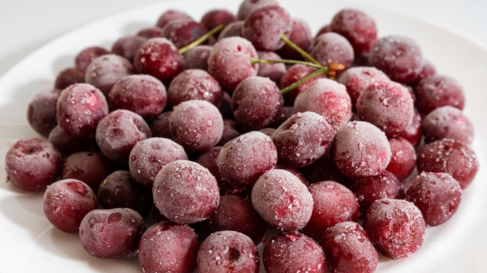 An overhead and close-up shot of a pile of frozen fruits on a plate in a well lit area indoors