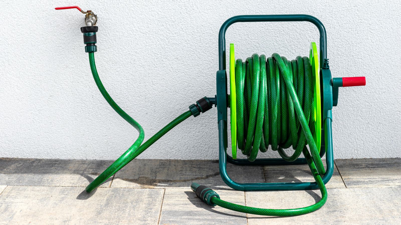 A close-up shot of a wound-up garden hose connected to a faucet, all situated in a garden area outdoors