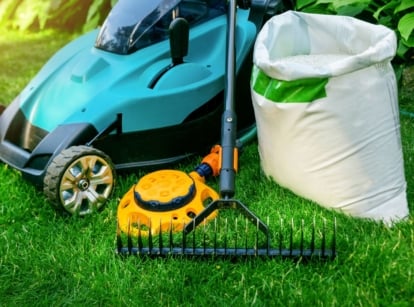 A close-up shot of several tools and equipment placed in a garden area, showcasing proper august lawn care