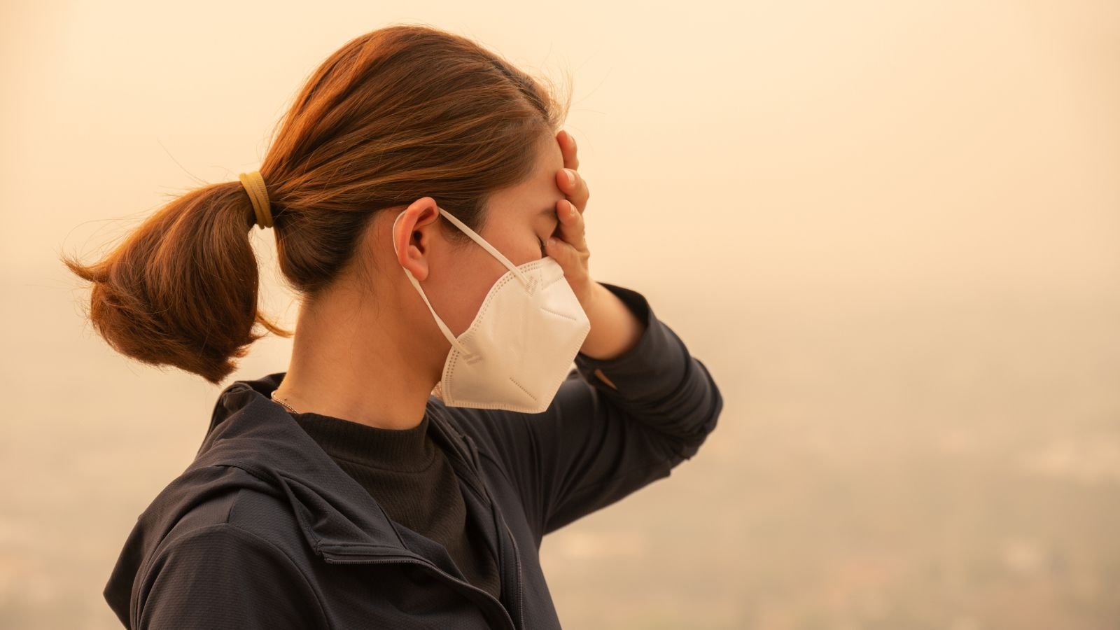 A shot of a person wearing a face mask distressing over an area covered in fumes