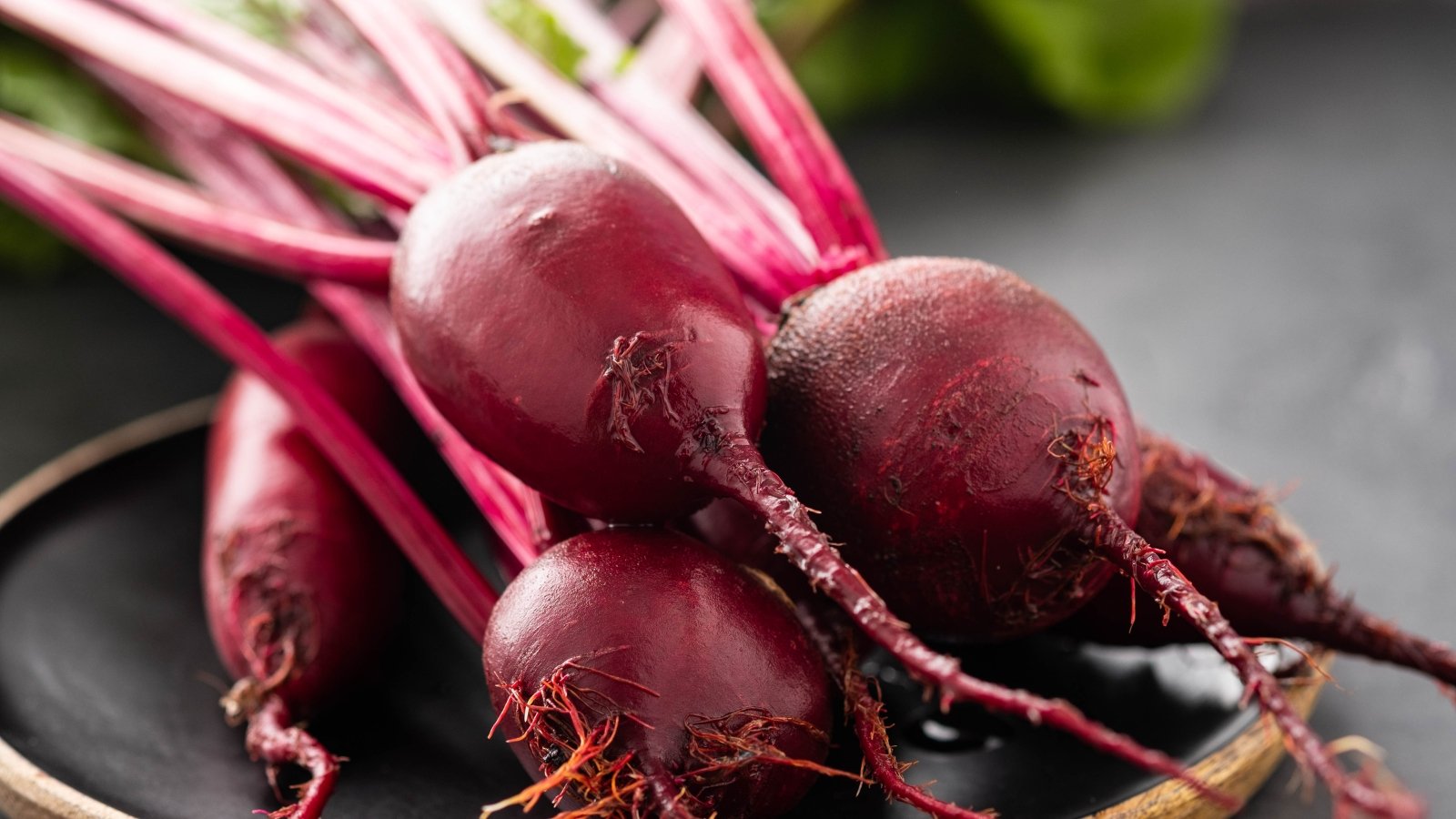 Freshly harvested beets with small round roots and green stems neatly arranged on a table.