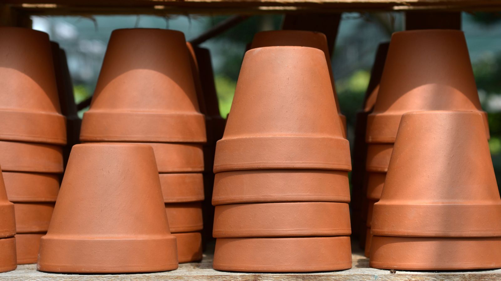 A close-up shot of a composition of empty terracotta planters all placed on top of each other in a well lit area outdoors