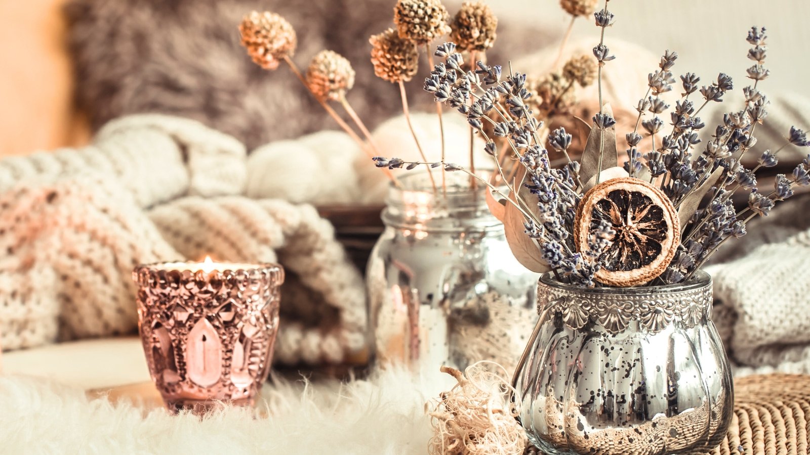 A silver mercury glass vase holds dried lavender spikes and dried globe amaranth flower heads, along with a slice of dried orange rind.