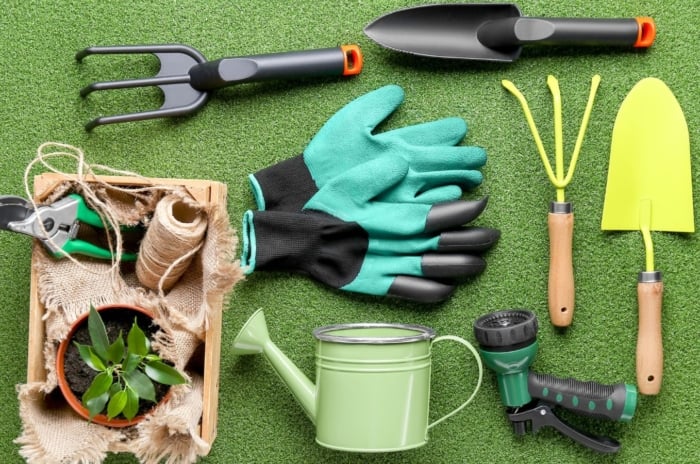 A flat lay shot of Luxury gardening gifts appearing to include gloves, trowels and other tools used for gardening, placed on a green fluffy surface