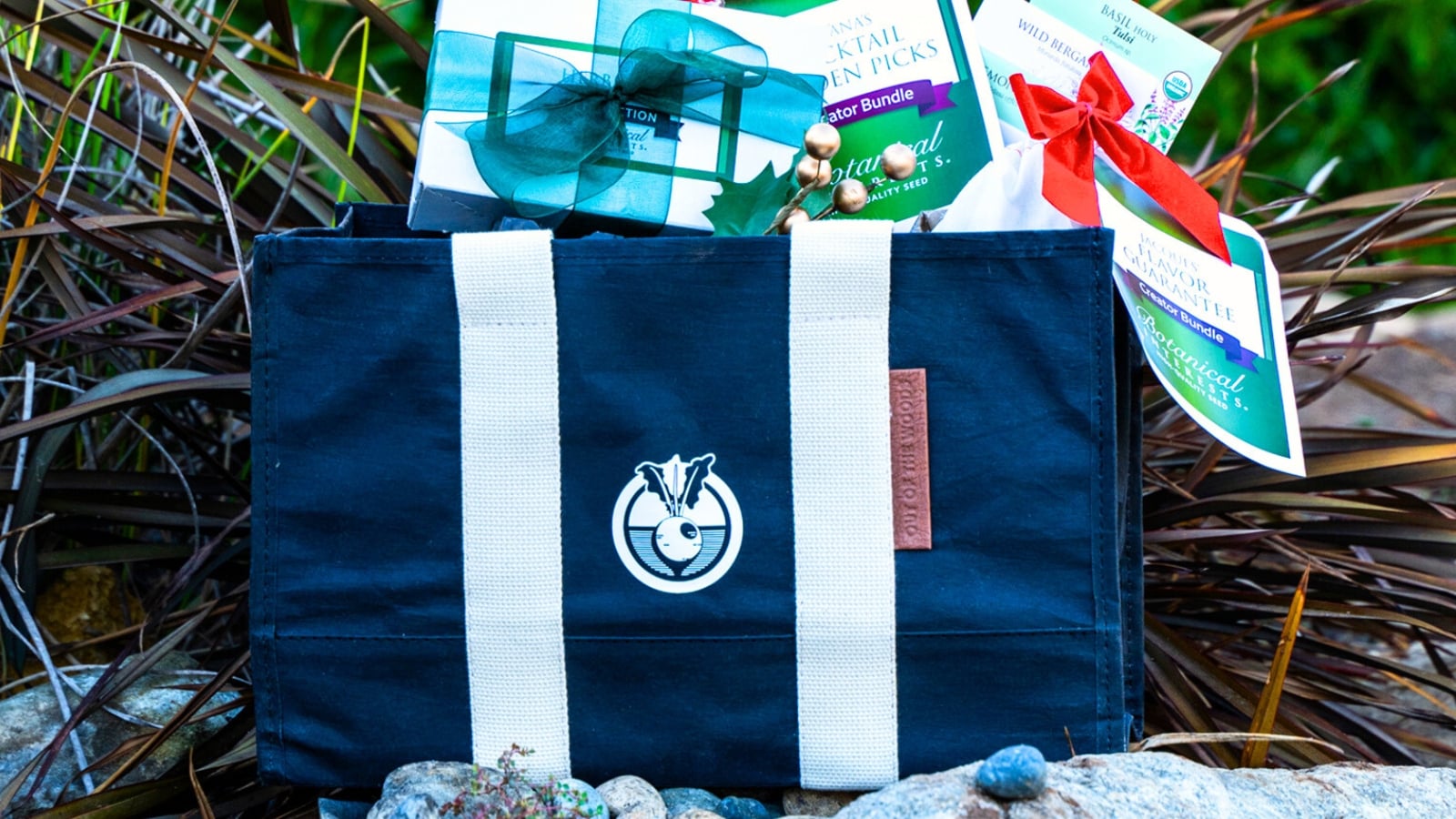 Black friday garden guide. A large blue branded bag with a visible logo is filled with assorted gardening supplies, including neatly packed gift sets of seeds.