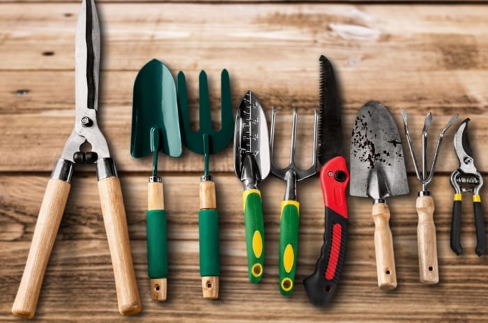 A close-up and overhead shot of a composition of gardening tools, placed on a wooden surface, showcasing garden tools before using