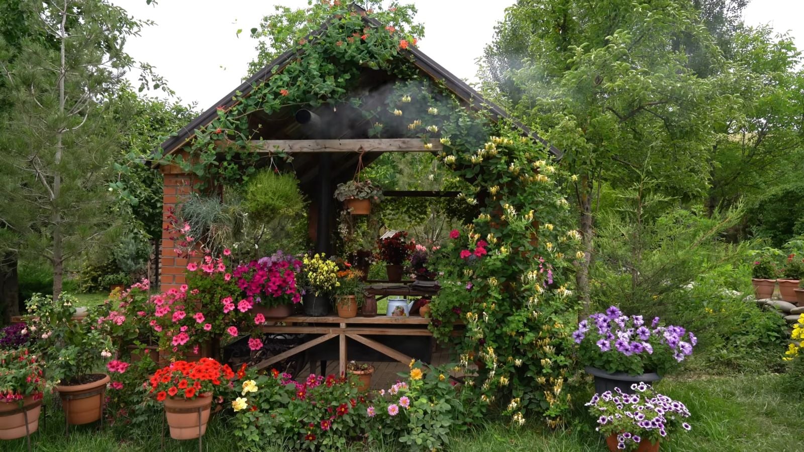 A close-up shot of a gazebo with several plants and flowers near its base and some growing on its pillars