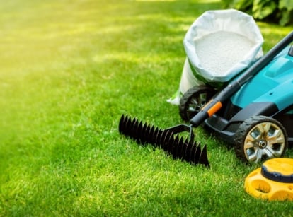 A close-up shot of several gardening tools and equipment, placed on clean turf, showcasing April lawn care