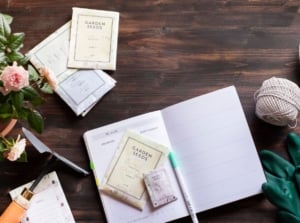 A close-up and overhead shot of several tools, equipment, seeds, and a notebook, showcasing mom gardening gifts